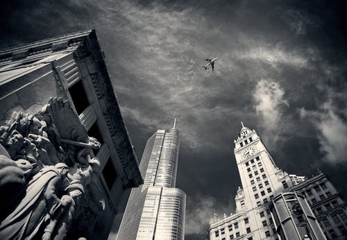 飞机飞越混凝土建筑物和雕像在灰度摄影 · 免费素材图片
