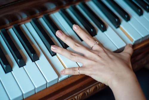用两根手指的人使用的棕色木制钢琴 · 免费素材图片