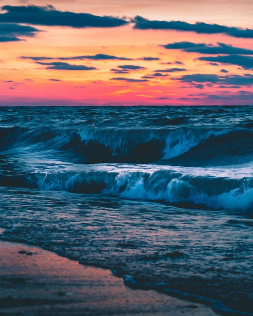海浪在日落时在岸上崩溃 · 免费素材图片