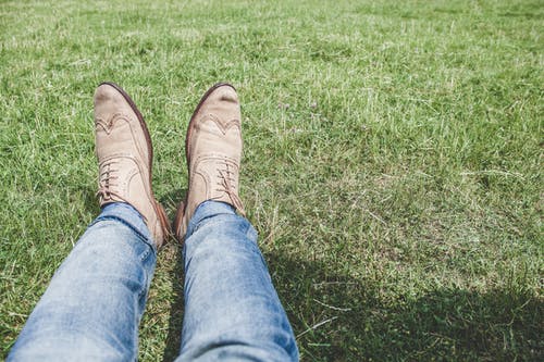 穿着蓝色牛仔牛仔裤，坐在草地上的人 · 免费素材图片