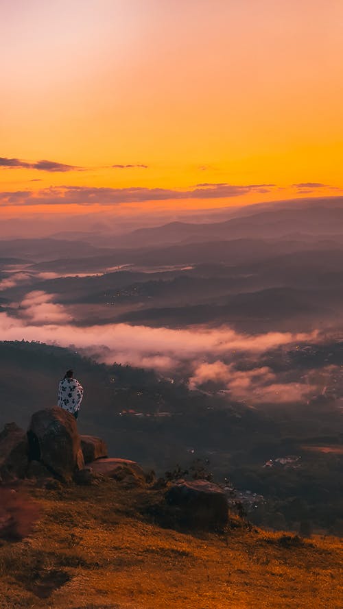 坐在岩石上的人 · 免费素材图片