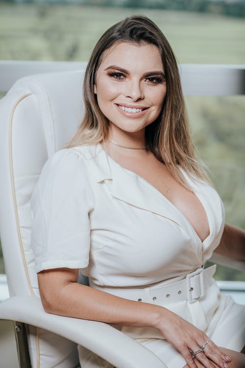 女人坐在白色皮革扶手椅上 · 免费素材图片