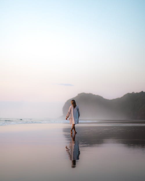 在清晨在湿的沙滩上行走的匿名女人 · 免费素材图片
