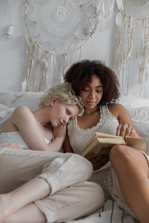 爱多样的同性情侣在床上放松与书 · 免费素材图片