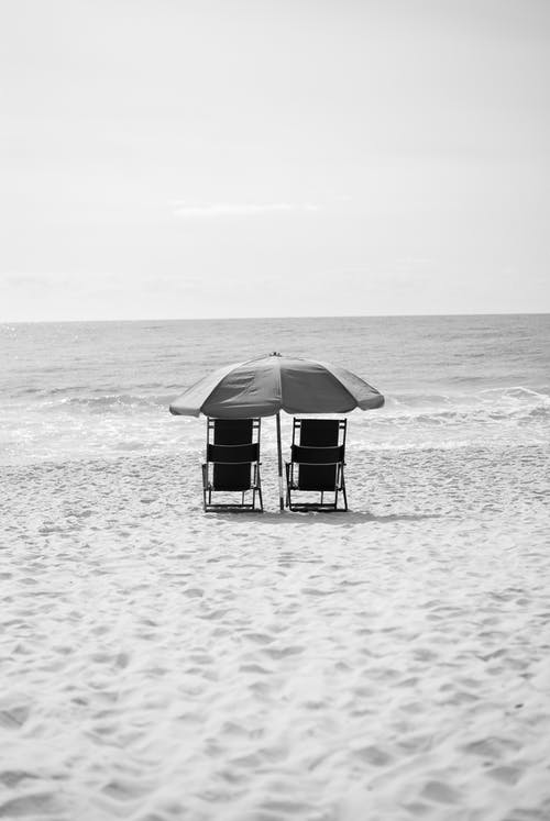 两把扶手椅在水体附近的灰度摄影 · 免费素材图片