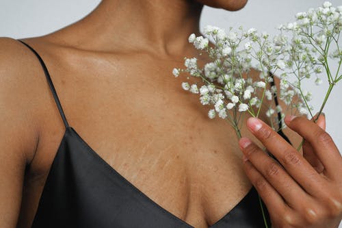 黑色意粉表带顶部拿着白花的女人 · 免费素材图片