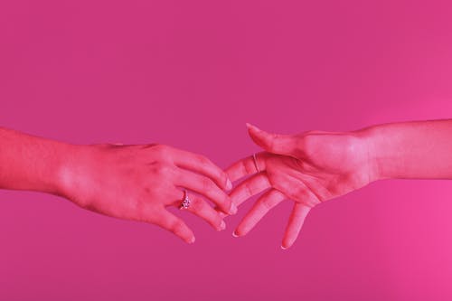 触摸粉红色背景的手的照片 · 免费素材图片