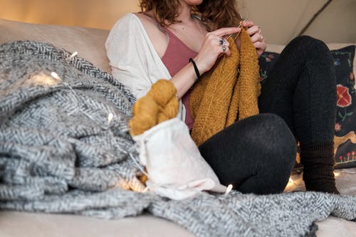针织毛衣时坐在沙发上的女人 · 免费素材图片