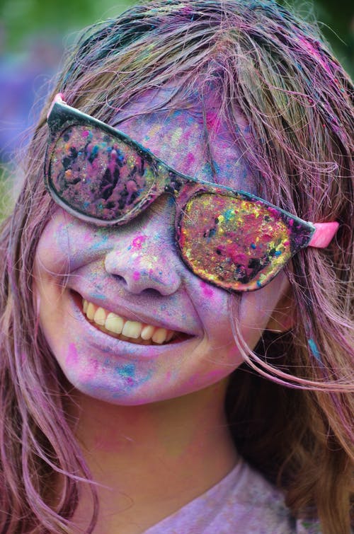 黑色框架太阳镜的女孩，她脸上的颜色从颜色运行微笑 · 免费素材图片