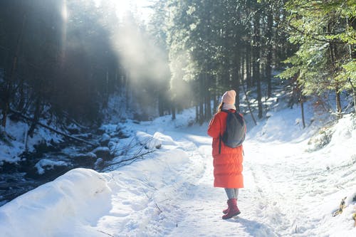 红色外套的女孩站立在积雪的地面上 · 免费素材图片