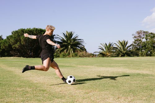 黑色的t恤和黑色的短裤，踢足球的女人 · 免费素材图片