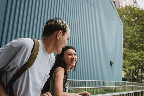 笑多种族的夫妇在城市篱笆附近聊天 · 免费素材图片