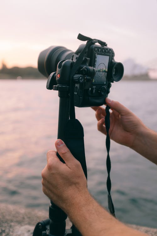 拿着黑单反相机的人 · 免费素材图片