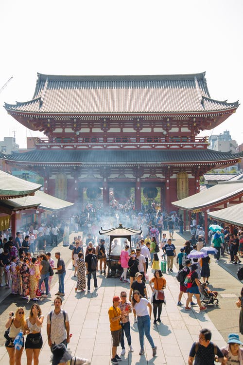 匿名旅行者在城里老年的亚洲庙宇附近的人行道上 · 免费素材图片