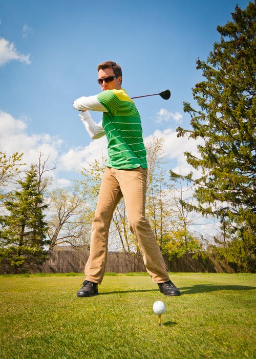 拿着黑色高尔夫俱乐部的绿色和白色条纹长袖衬衫的男人 · 免费素材图片
