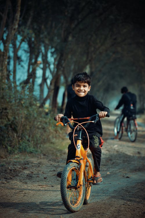 黑色长袖衬衫骑橙色自行车的男孩 · 免费素材图片