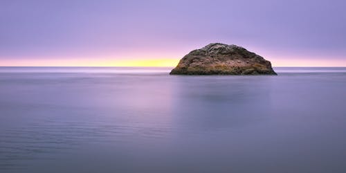日落期间海岛在海上的照片 · 免费素材图片