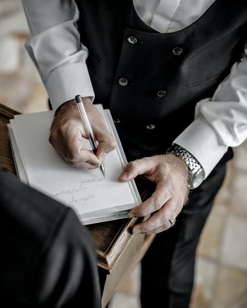黑西装写在白书上的男人 · 免费素材图片