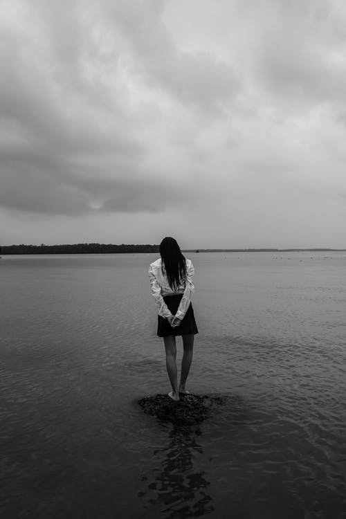 站立在水体的一块岩石的妇女 · 免费素材图片