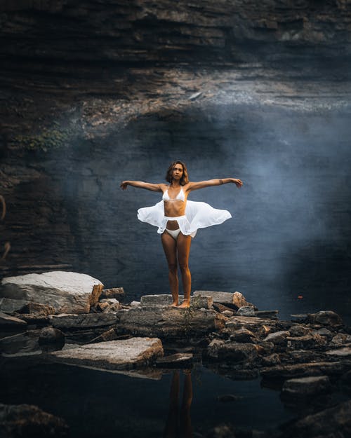 白衬衫和白色短裤站在棕色的岩石上的女人 · 免费素材图片