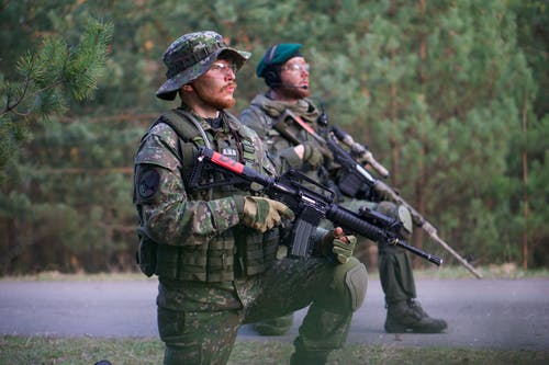 2名穿着绿色迷彩制服的手持步枪的人 · 免费素材图片