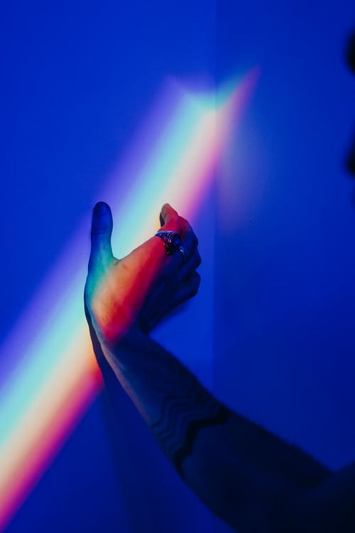 人的手触碰着彩虹色的墙壁的照片 · 免费素材图片