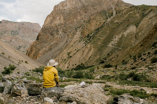 匿名的徒步旅行者享受山景坐在山谷的石头上 · 免费素材图片