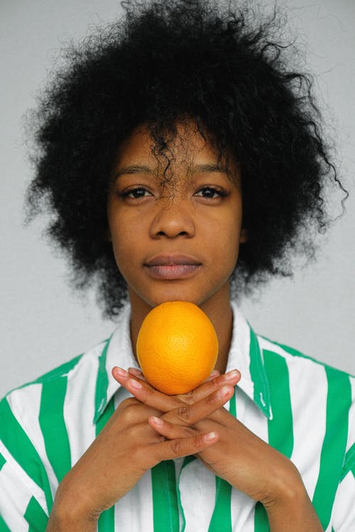 拿着橙色果子的绿色和白色衬衣的妇女 · 免费素材图片