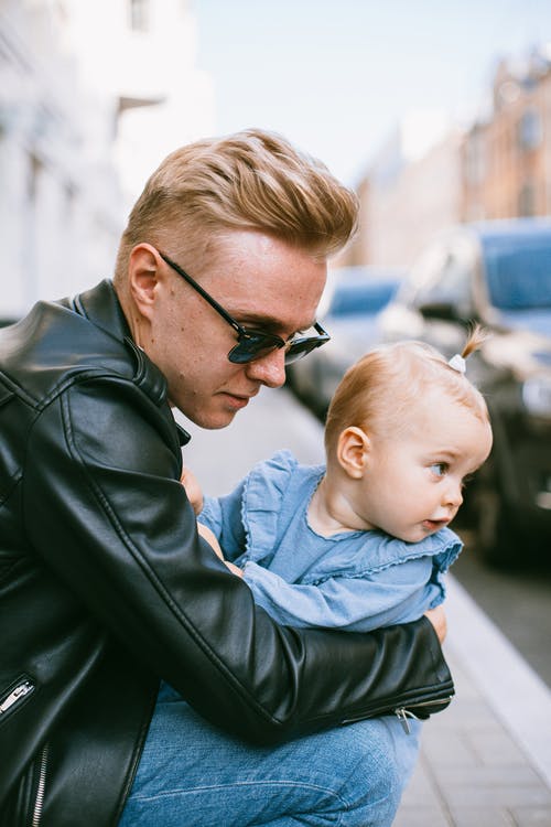 抱着婴儿的黑色皮夹克的男人 · 免费素材图片