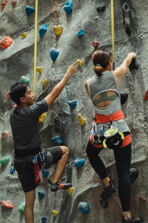 男性教练在攀岩墙上不露面的女人 · 免费素材图片