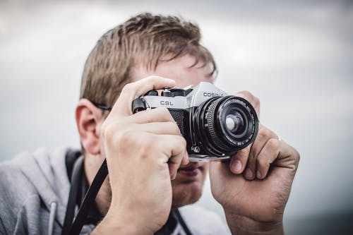 该名男子手持黑银桥相机在白天拍照 · 免费素材图片