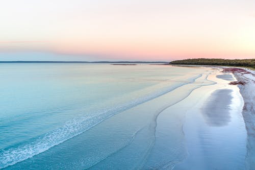 在日落时波浪海洋附近的沙质海岸 · 免费素材图片