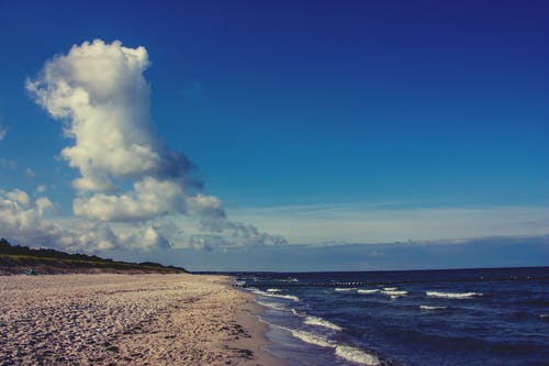 在白云和蓝天沙旁边的水域 · 免费素材图片