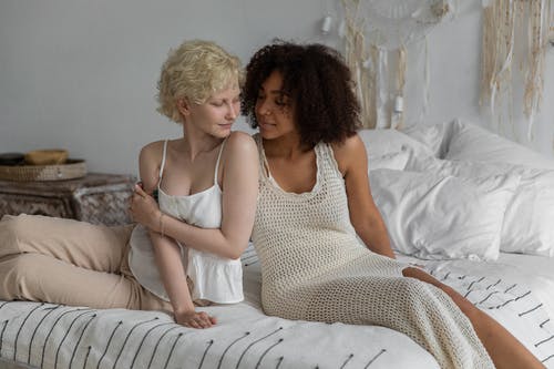 积极多样的女同性恋夫妇在舒适的床上拥抱 · 免费素材图片