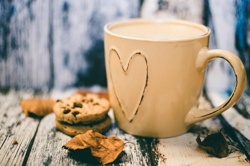 米色陶瓷心形杯咖啡，饼干食品旁边 · 免费素材图片
