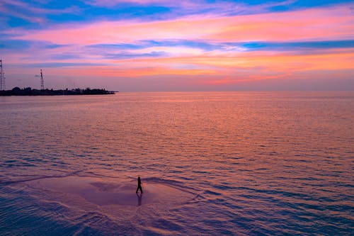 在日落海滩上散步的人的身影 · 免费素材图片