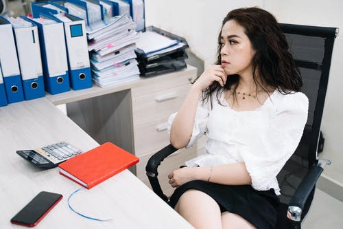 坐在黑办公室滚动椅子上的白衬衫的女人 · 免费素材图片