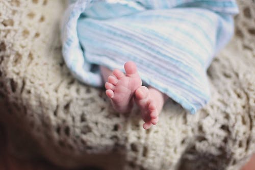 一条蓝色毯子下面的婴儿脚 · 免费素材图片