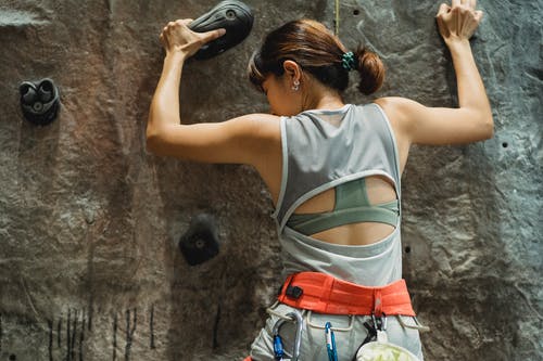 在岩石墙上爬的运动型女人 · 免费素材图片