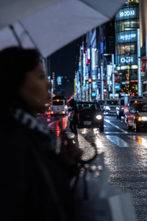 女人站在白色雨伞下的街道上 · 免费素材图片