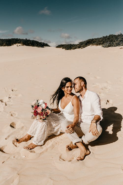夫妻坐在沙滩上的照片 · 免费素材图片