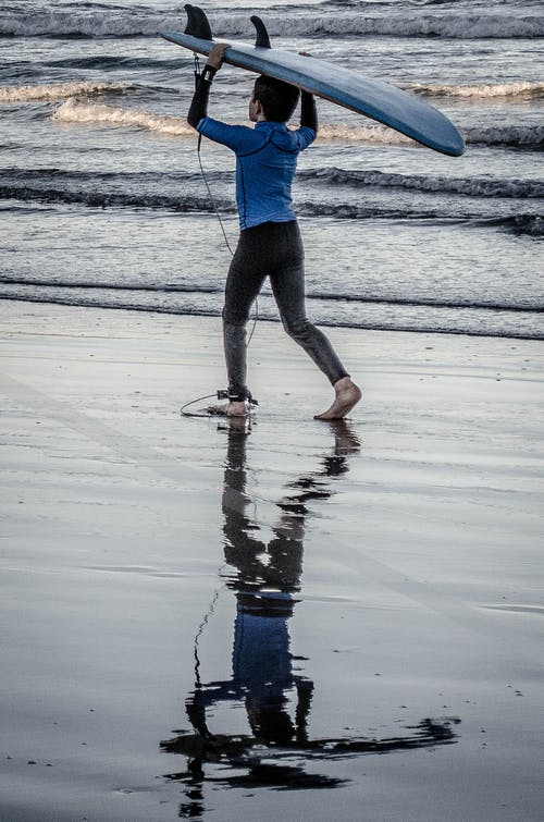 男孩抱着蓝色的冲浪板 · 免费素材图片