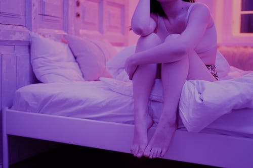 女人坐在白色的床上 · 免费素材图片