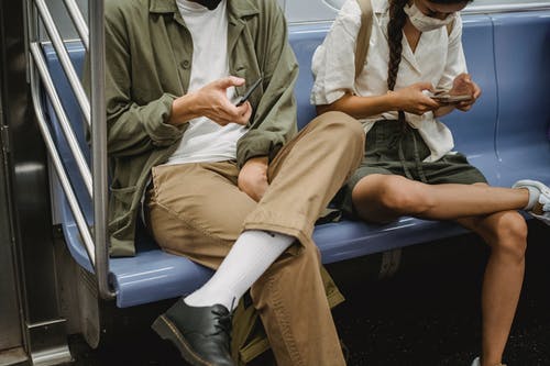 裁剪浏览地铁车厢中的智能手机的夫妇 · 免费素材图片