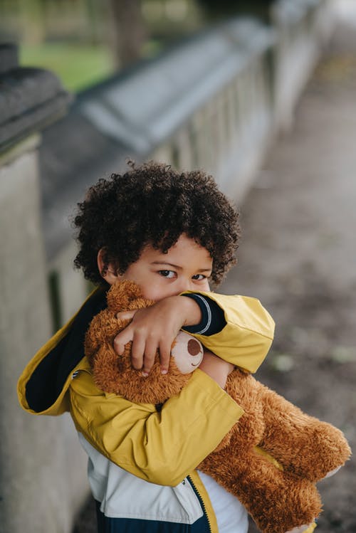 性格开朗的黑人男孩，在大街上抱着玩具熊 · 免费素材图片