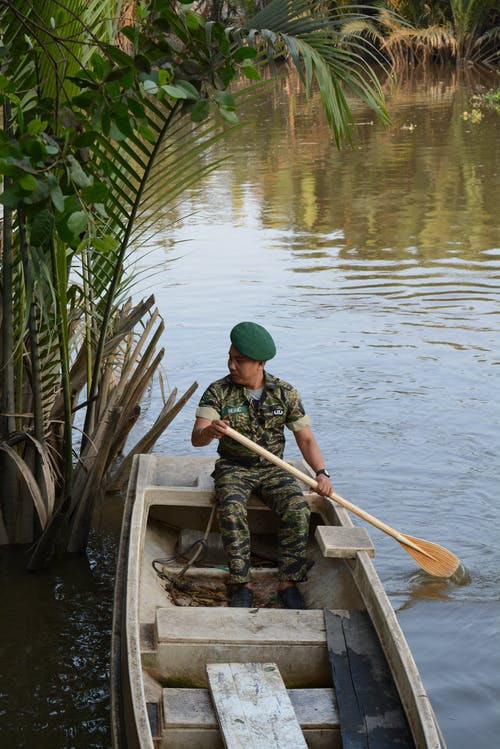 穿着绿色军服的人骑着一条船 · 免费素材图片