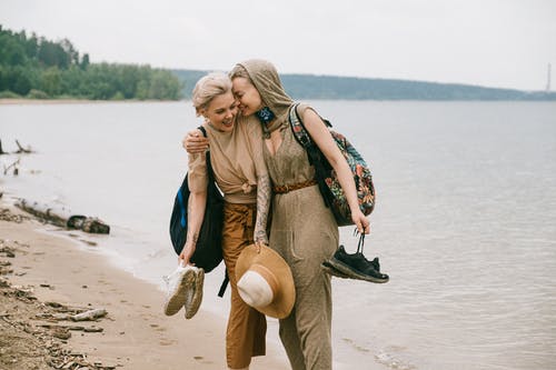 妇女站在海滩上拥抱的照片 · 免费素材图片