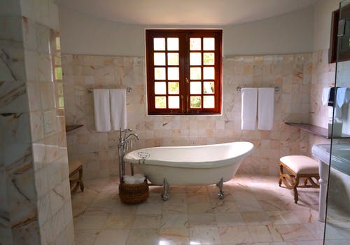 白色瓷砖浴室附近棕色框透明玻璃窗上的白色浴缸 · 免费素材图片