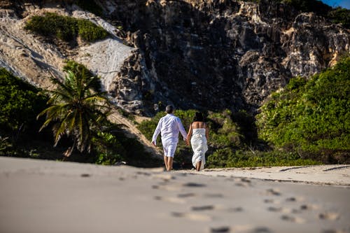 情侣牵手走在沙滩上的低角度照片 · 免费素材图片