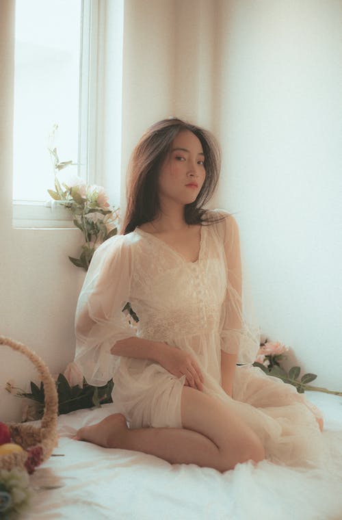 坐在窗户旁边的女人的照片 · 免费素材图片